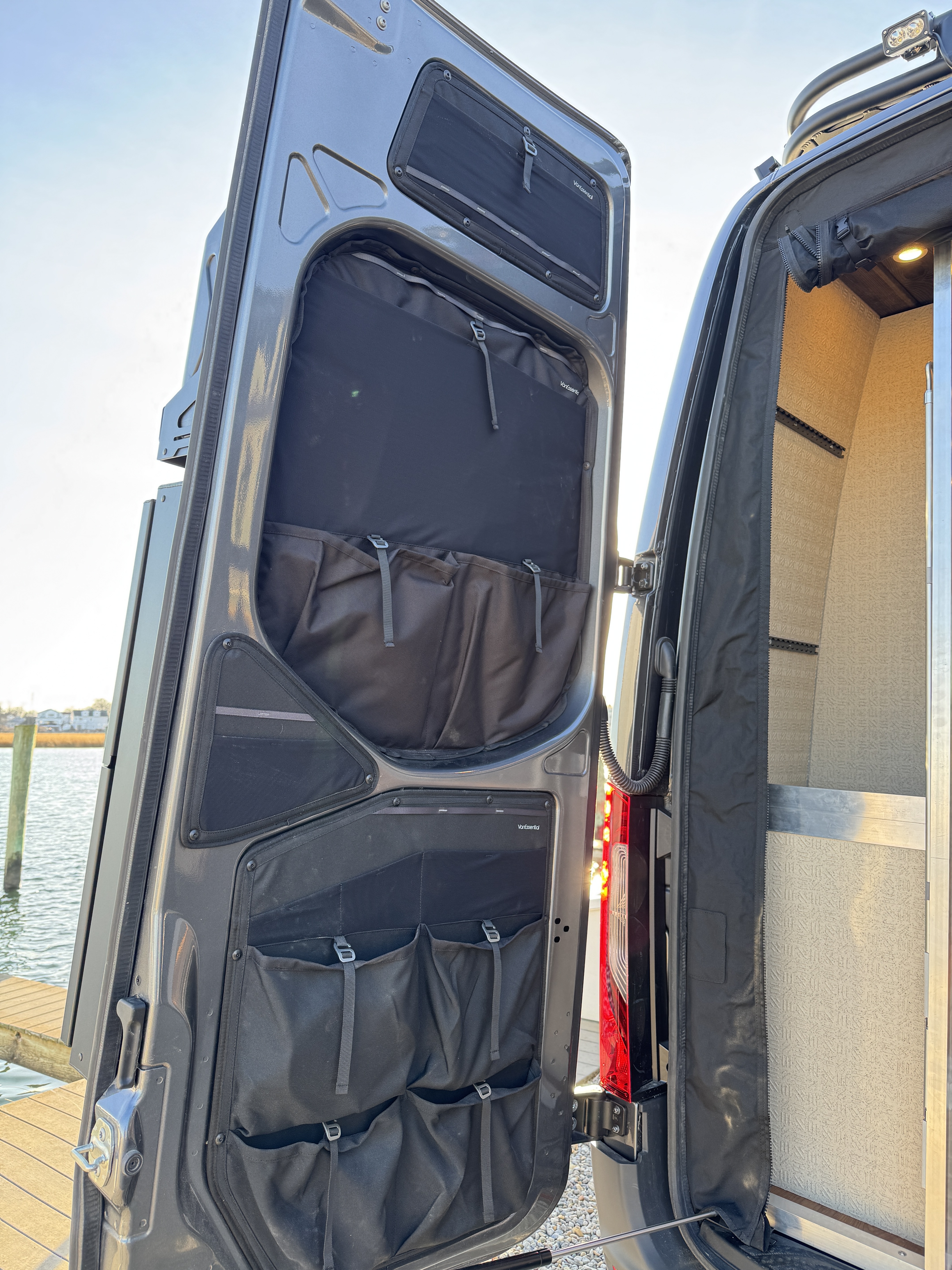 Baja Sprinter 170 4x4 — rear doors open showing VanEssential door storage organizers with bathroom and cabin interior visible