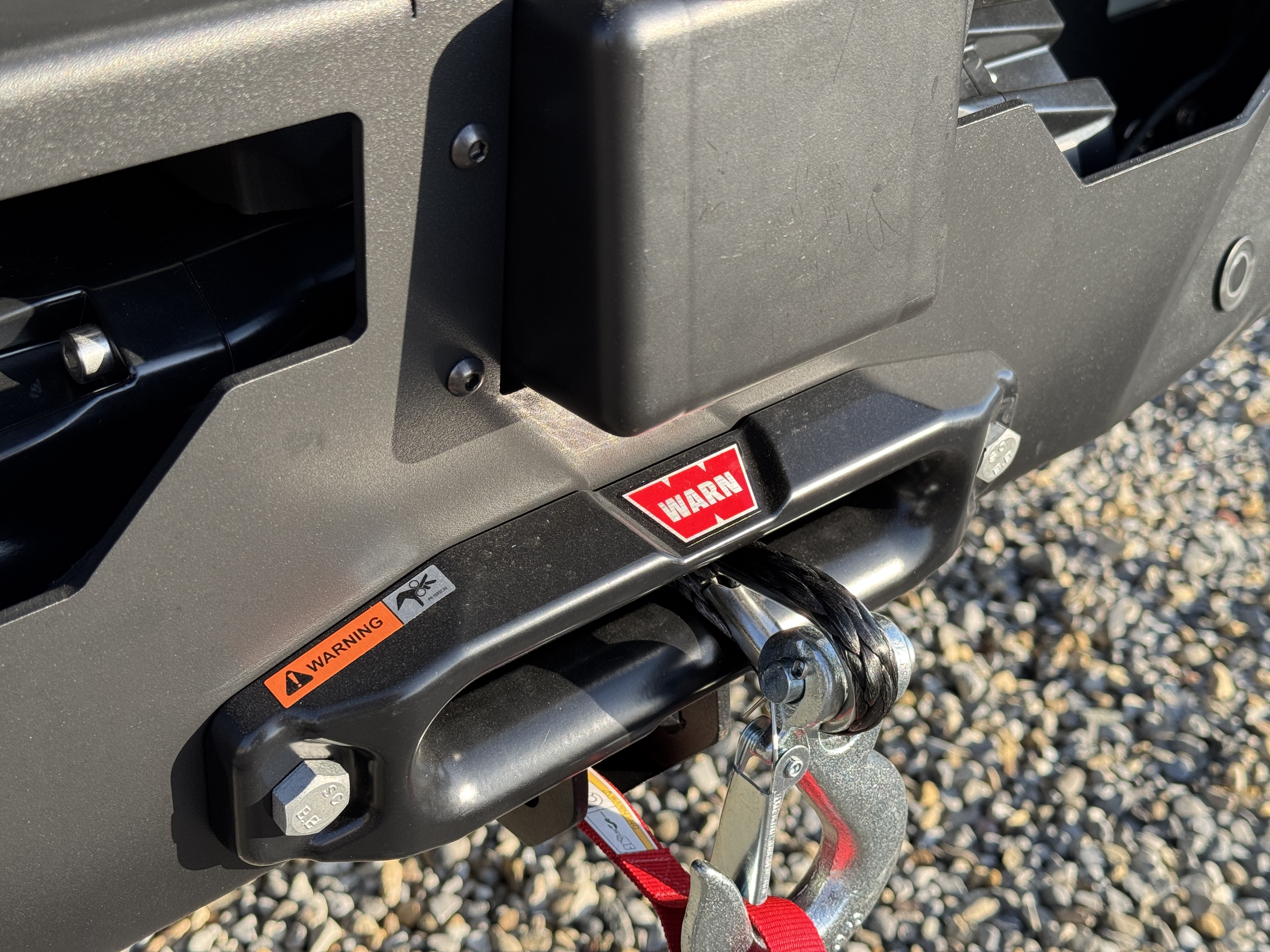 Baja Sprinter 170 4x4 — WARN recovery winch close-up mounted in the front bumper with safety warning label and synthetic line