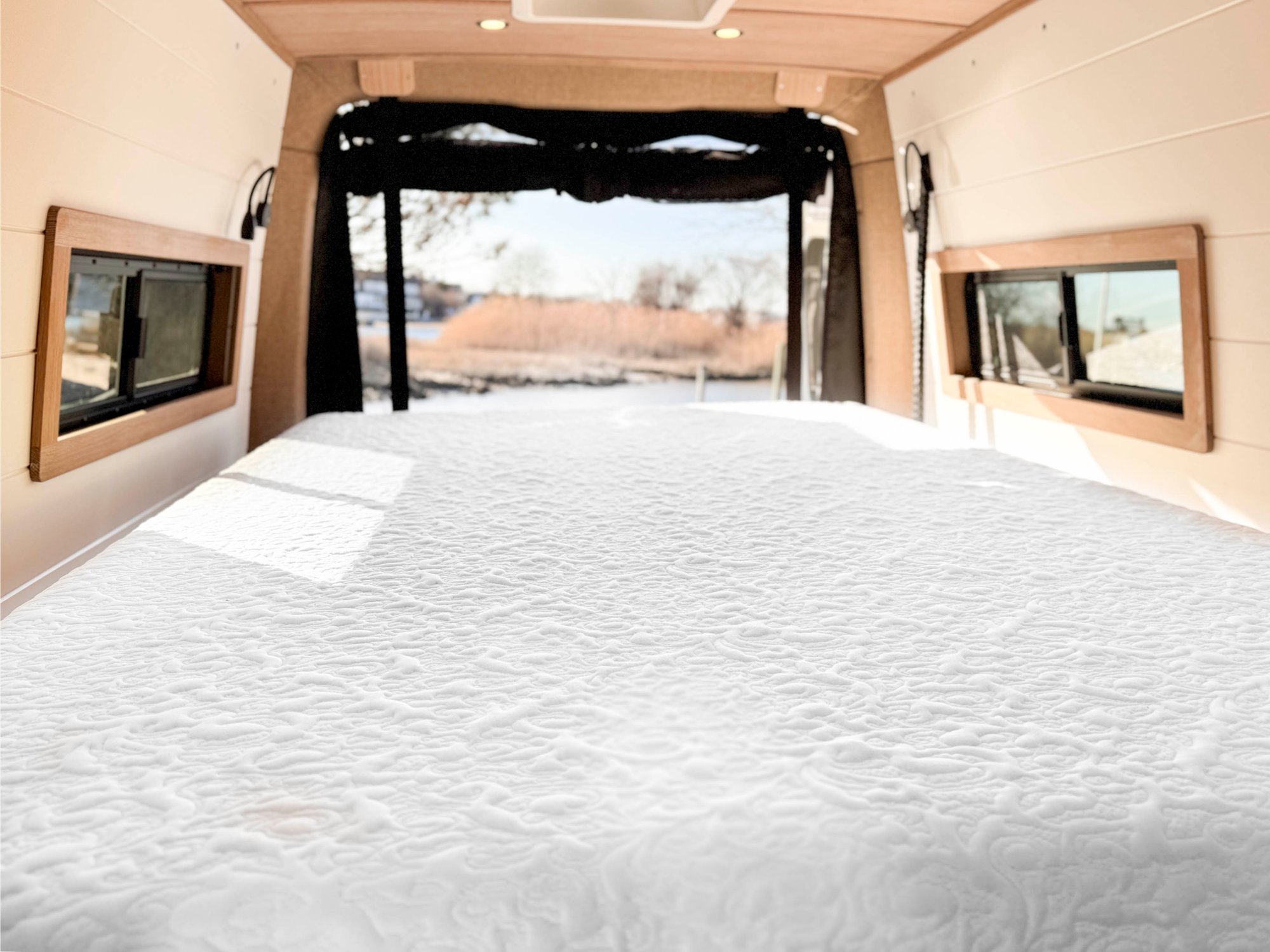 The Loft with the north-south lift bed lowered into night mode — a full made bed spanning the rear, doors open to the marina