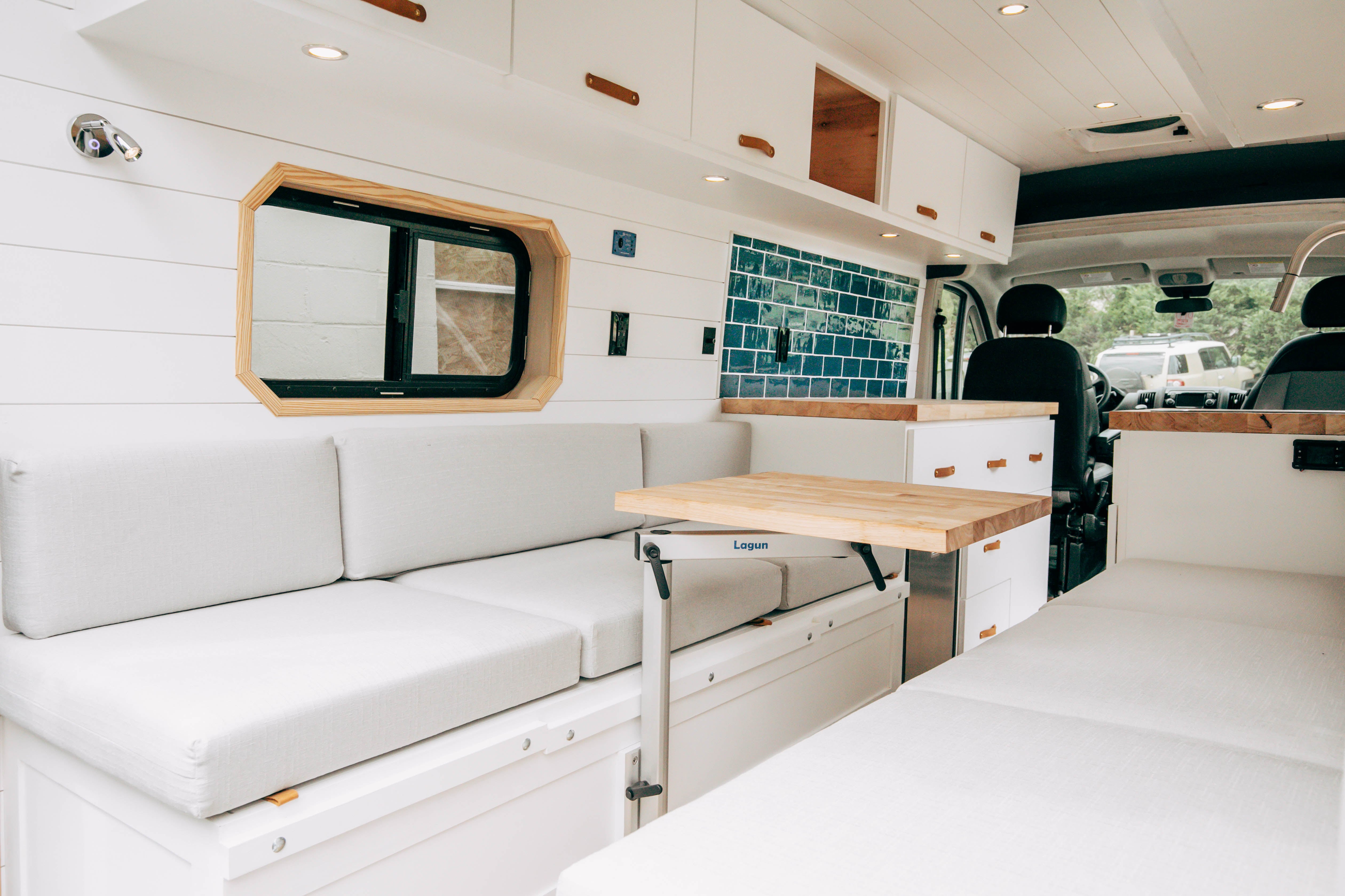 Riverside ProMaster 159 campervan bright white lounge with bench seating and wood-trimmed windows