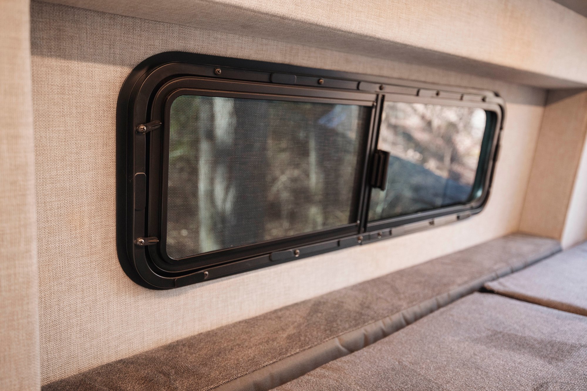 The Stoke — sliding screen window and bed cushion in the padded oatmeal fabric wall