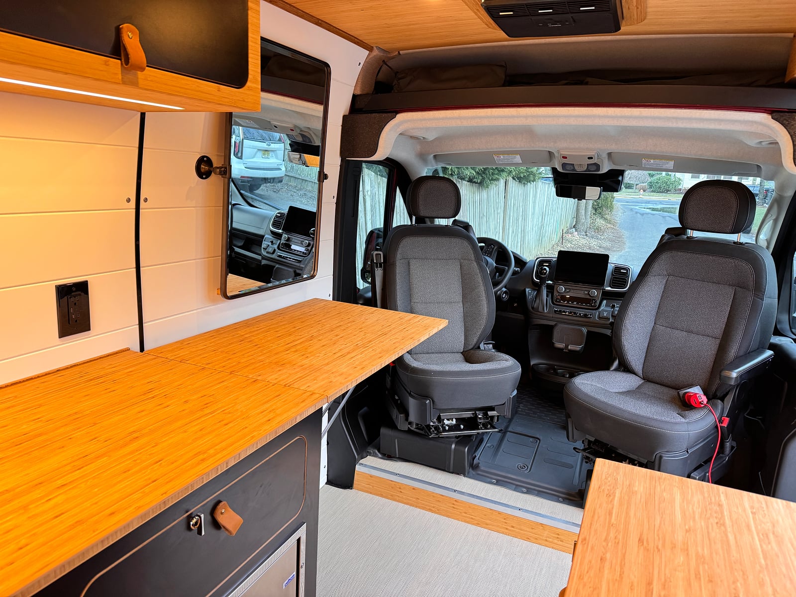 Bobal Mobile Salon — ProMaster interior with bamboo galley countertop, wall-mounted beauty mirror, and swivel cab seats