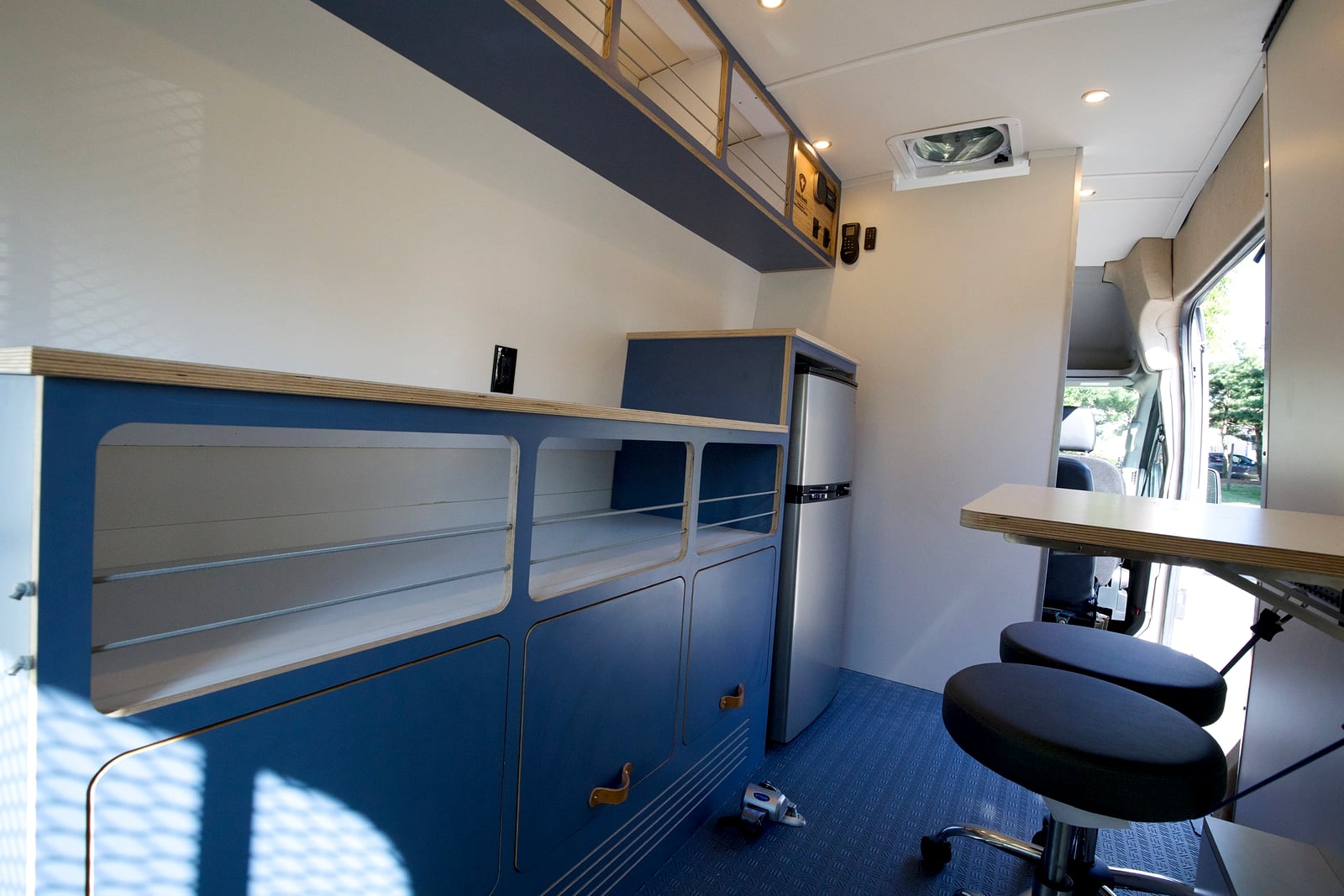 Northampton DCC electric Transit fleet — White Ext extended-mission interior with compact galley, refrigerator, open shelving, and fold-out work table