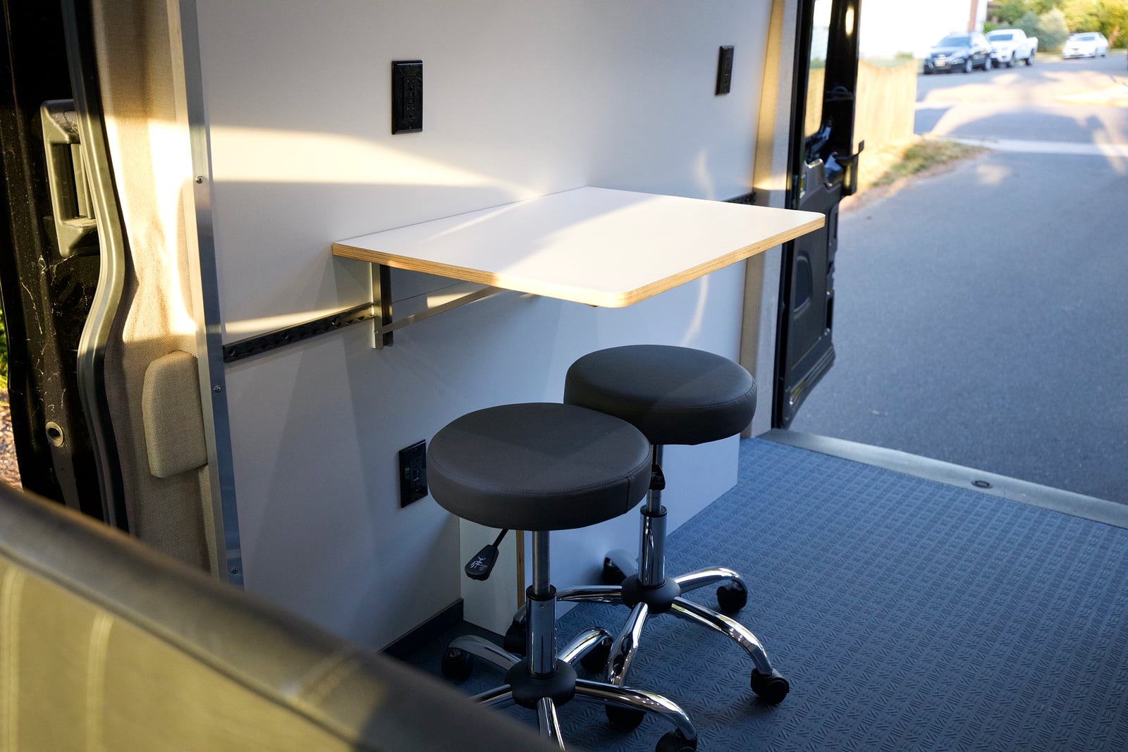 Northampton DCC electric Transit fleet — wall-mounted fold-down work table with rolling stools deployed