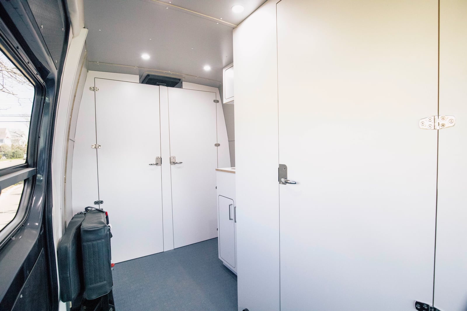 Sprinter mobile testing van — floor-to-ceiling white storage cabinetry with doors closed