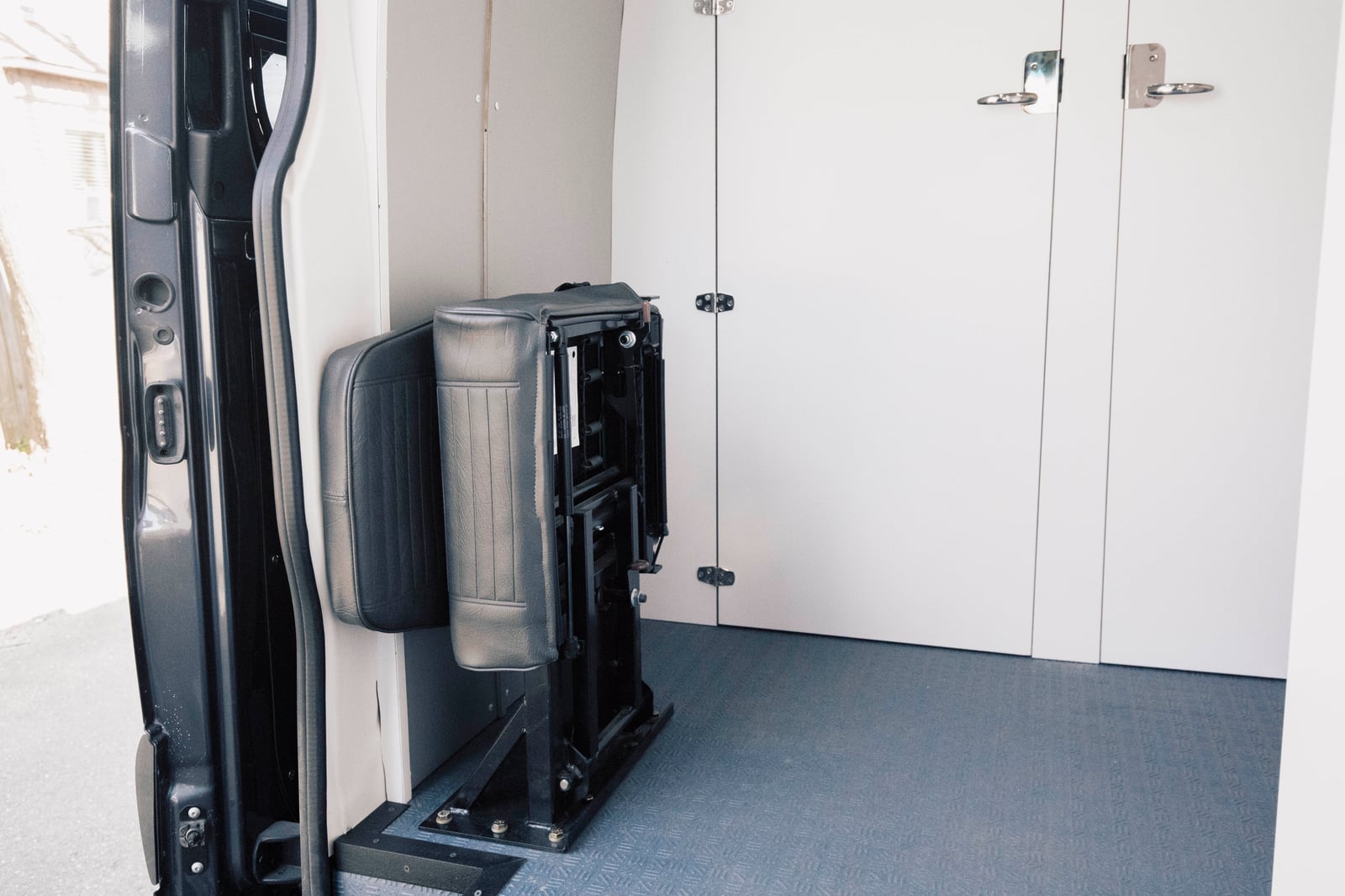 PROCEED Mobile Testing Van — fold-away jump seat at the sliding door against white wall panels