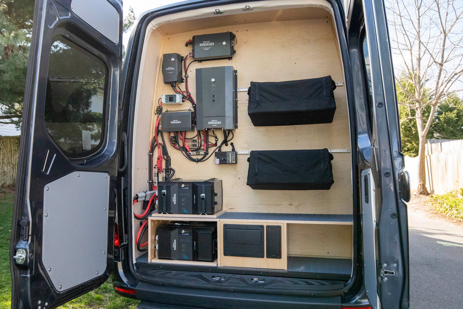 PROCEED Mobile Testing Van — rear electrical service wall with lithium battery bank, inverter, and charge controllers on baltic birch