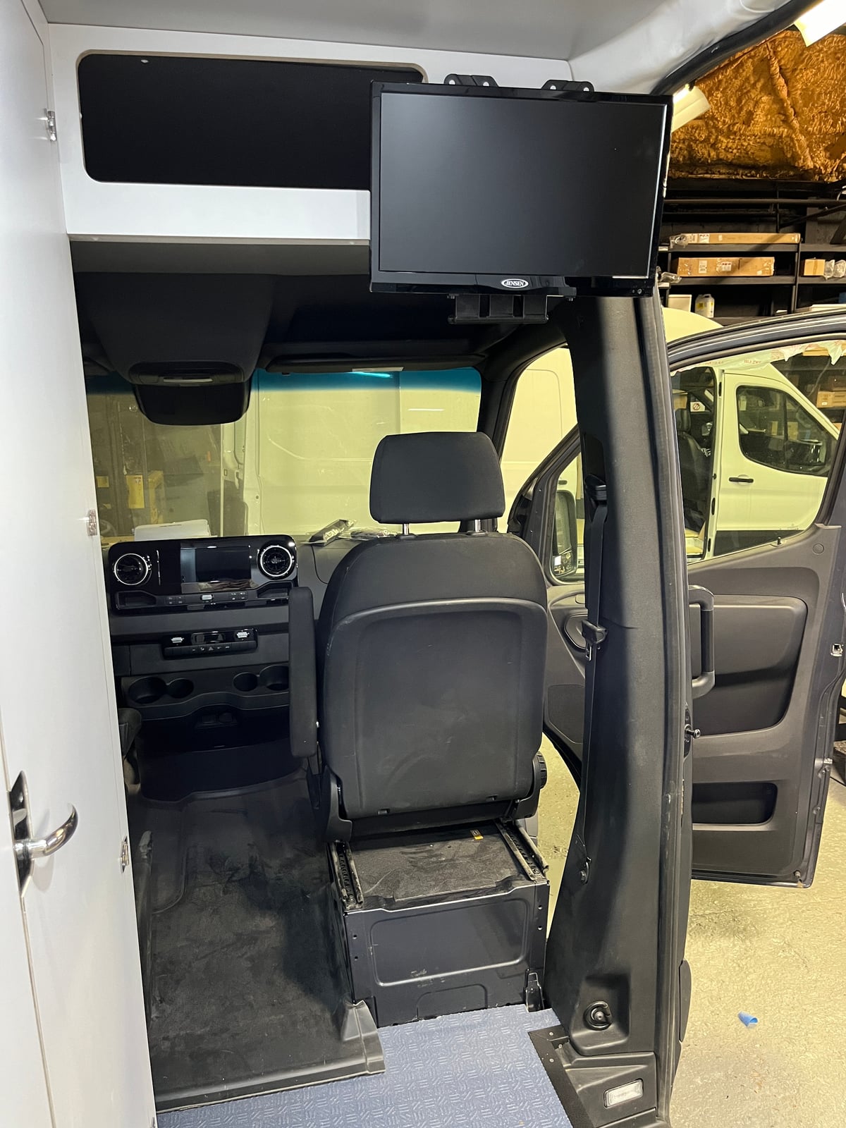 Sprinter mobile testing van — ceiling-mounted monitor above the swivel seat and overhead cabinetry