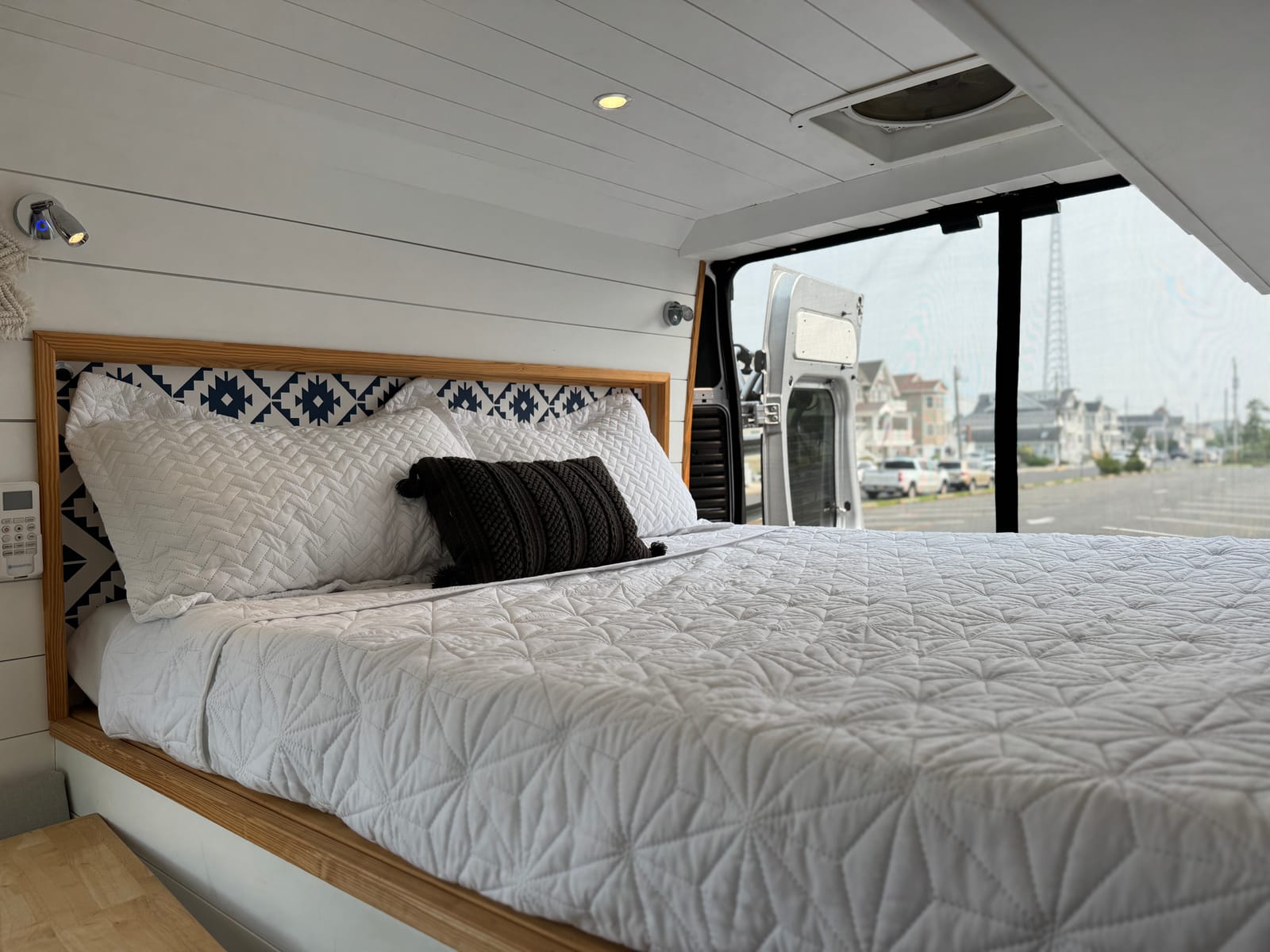 Full-size rear bed made up with white bedding, straight-on view