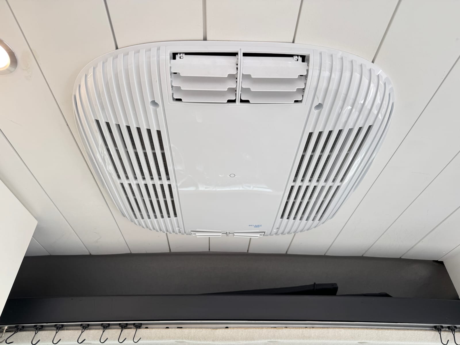 Interior ceiling-mounted air conditioner unit above the bed