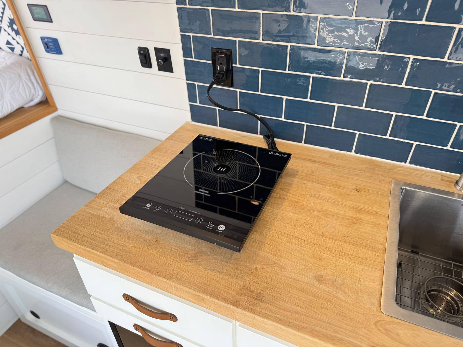 Portable induction cooktop set on the galley counter beside the sink