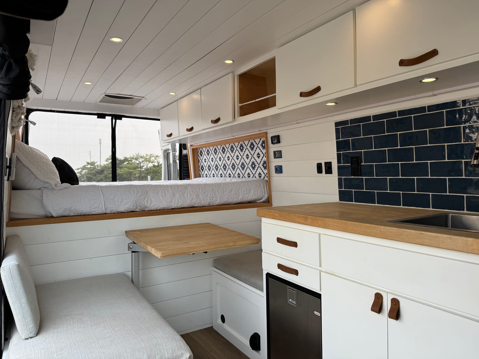 Galley and living area looking toward the rear with wood counter and white cabinetry