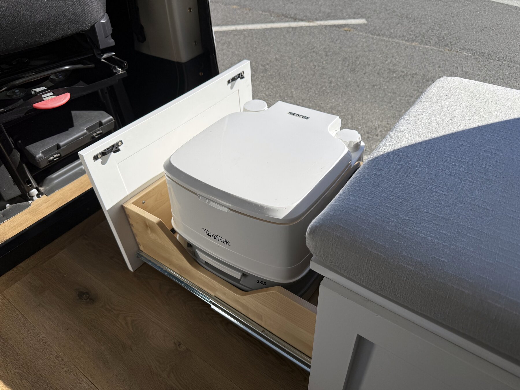 Thetford portable toilet on a slide-out tray under the bench seat