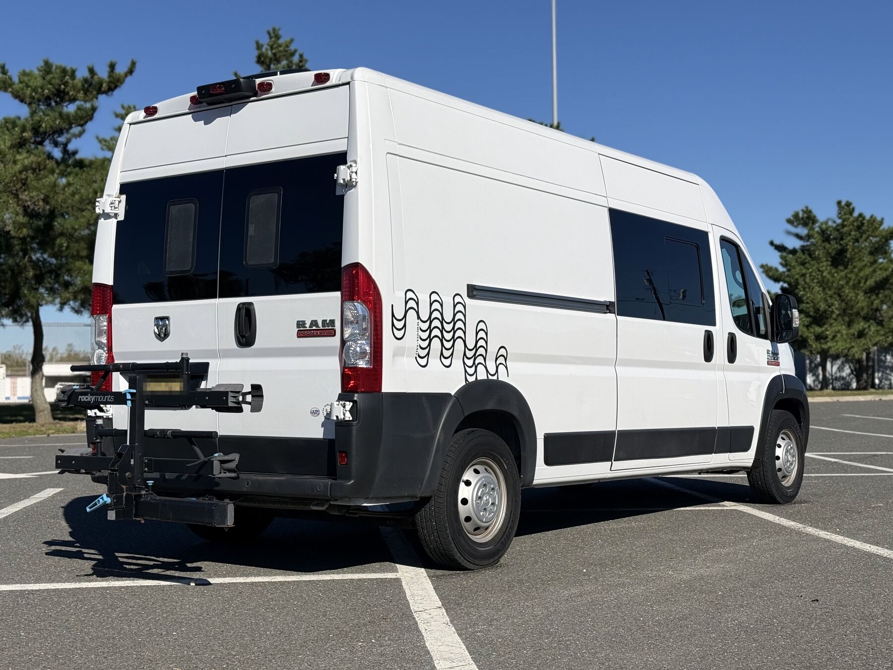 Rear three-quarter view of the van showing the wave decal, side windows and rear bike rack