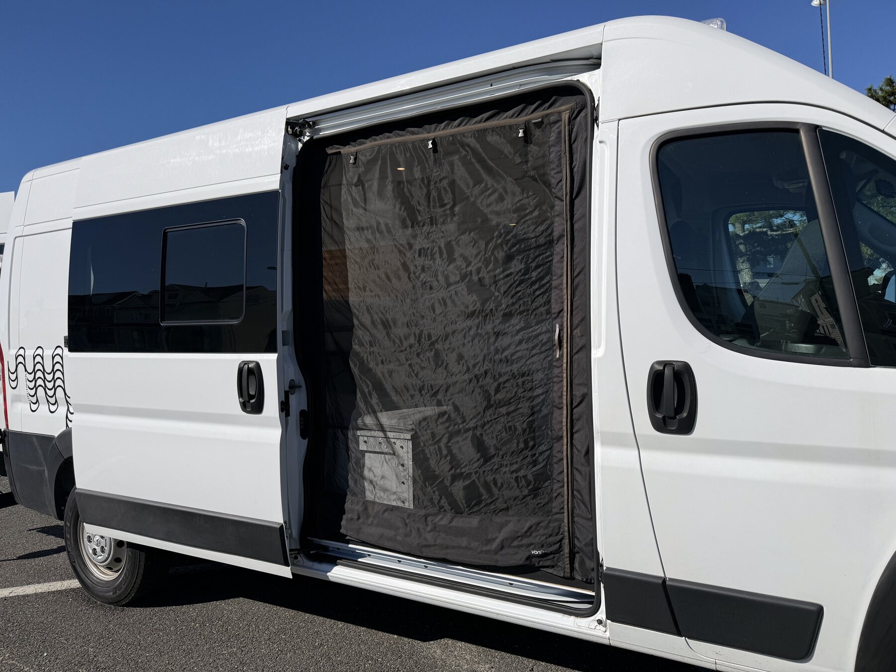 Passenger side with the sliding door open and a black mesh bug screen across the doorway