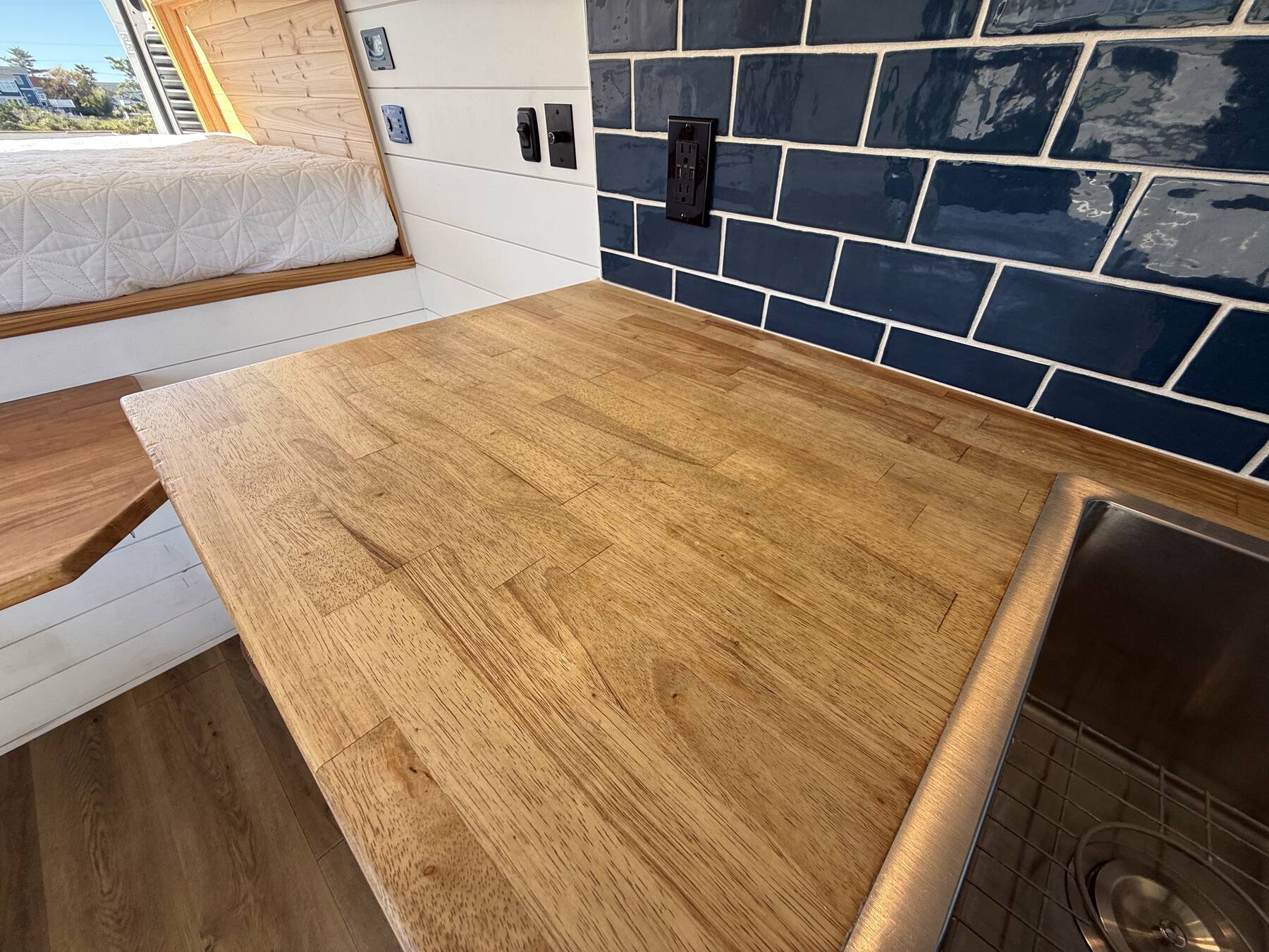 Butcher block counter running up to the navy subway tile backsplash