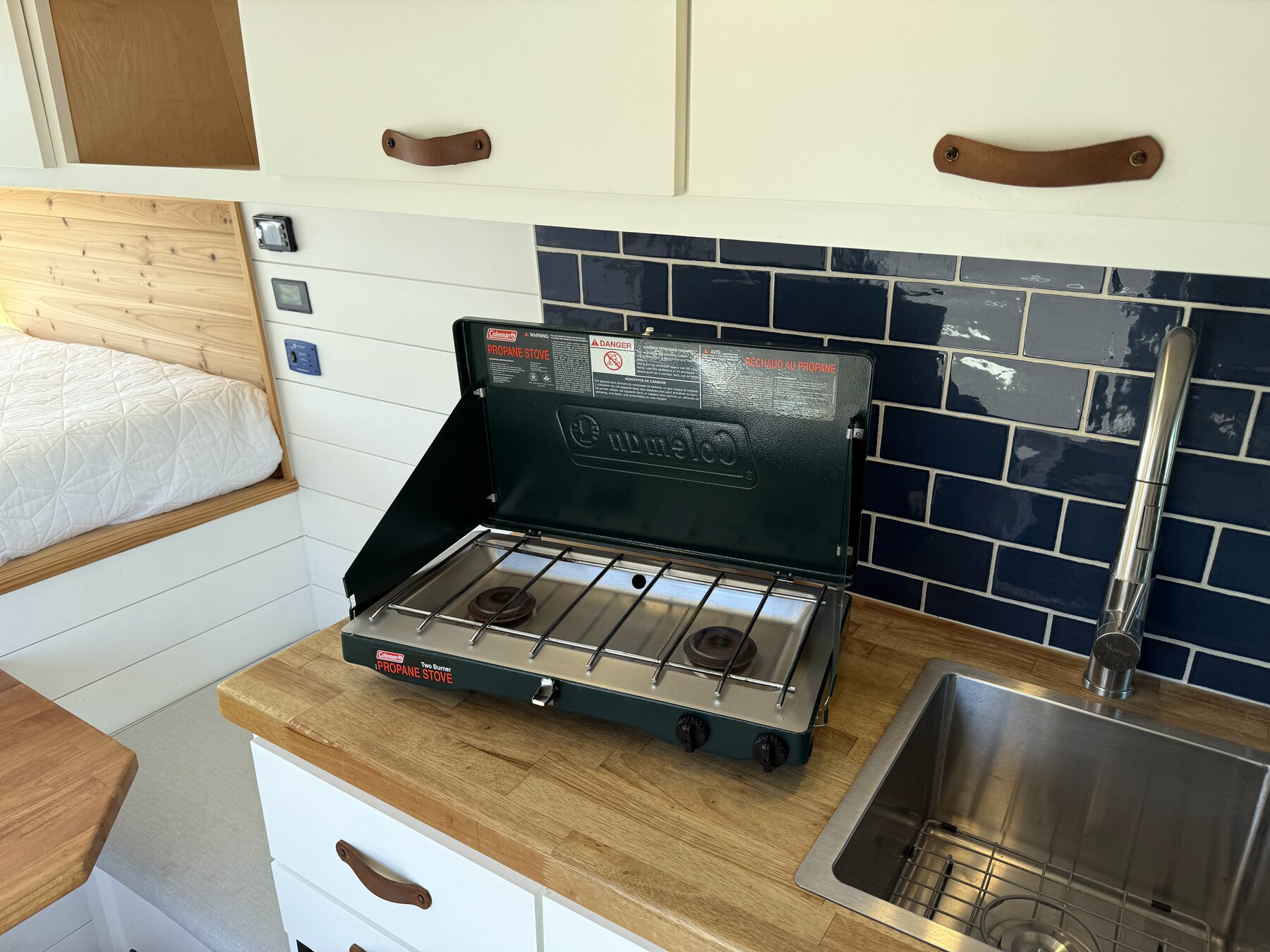 Coleman two-burner camp stove on the galley counter beside the sink