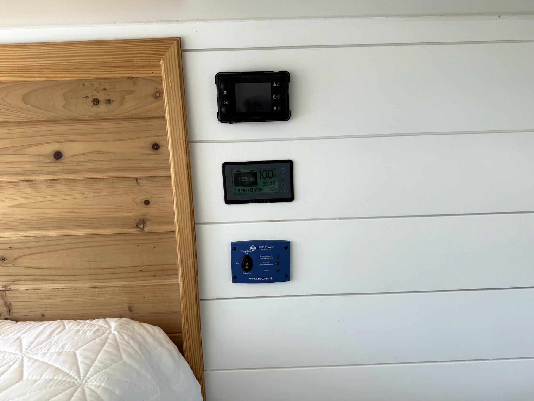 Three control panels mounted on the wall beside the bed
