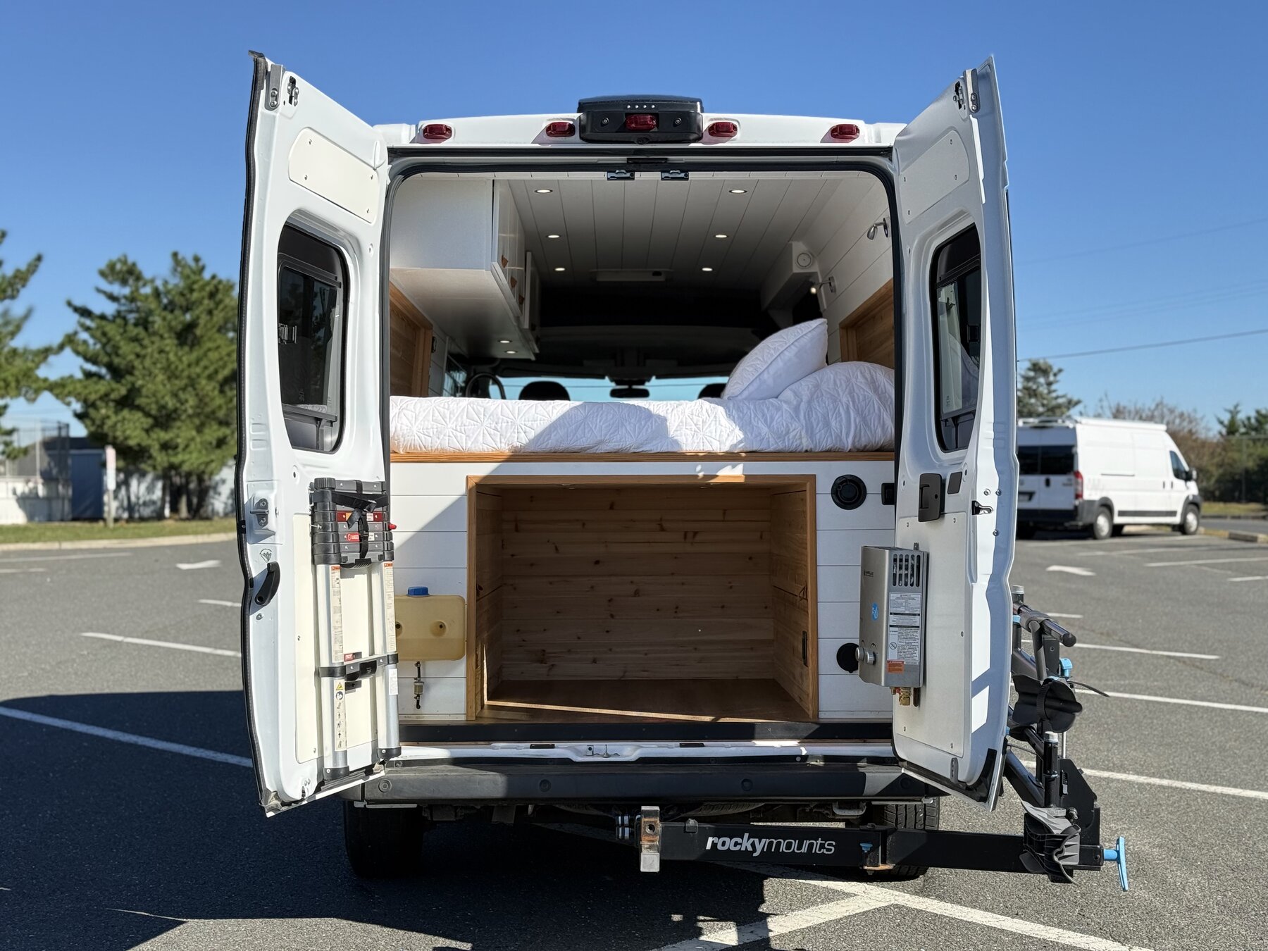 Rear doors open showing the bed platform above a cedar-lined gear garage