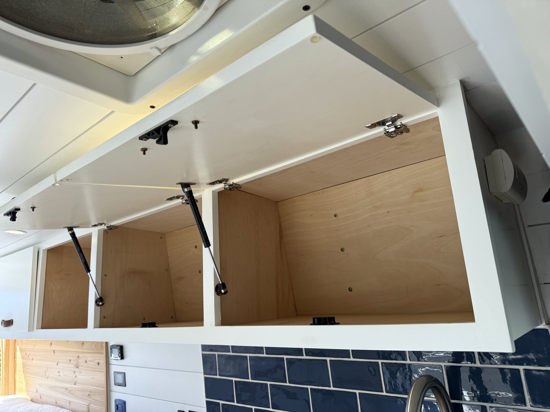 Overhead cabinets open, with gas struts holding the doors up
