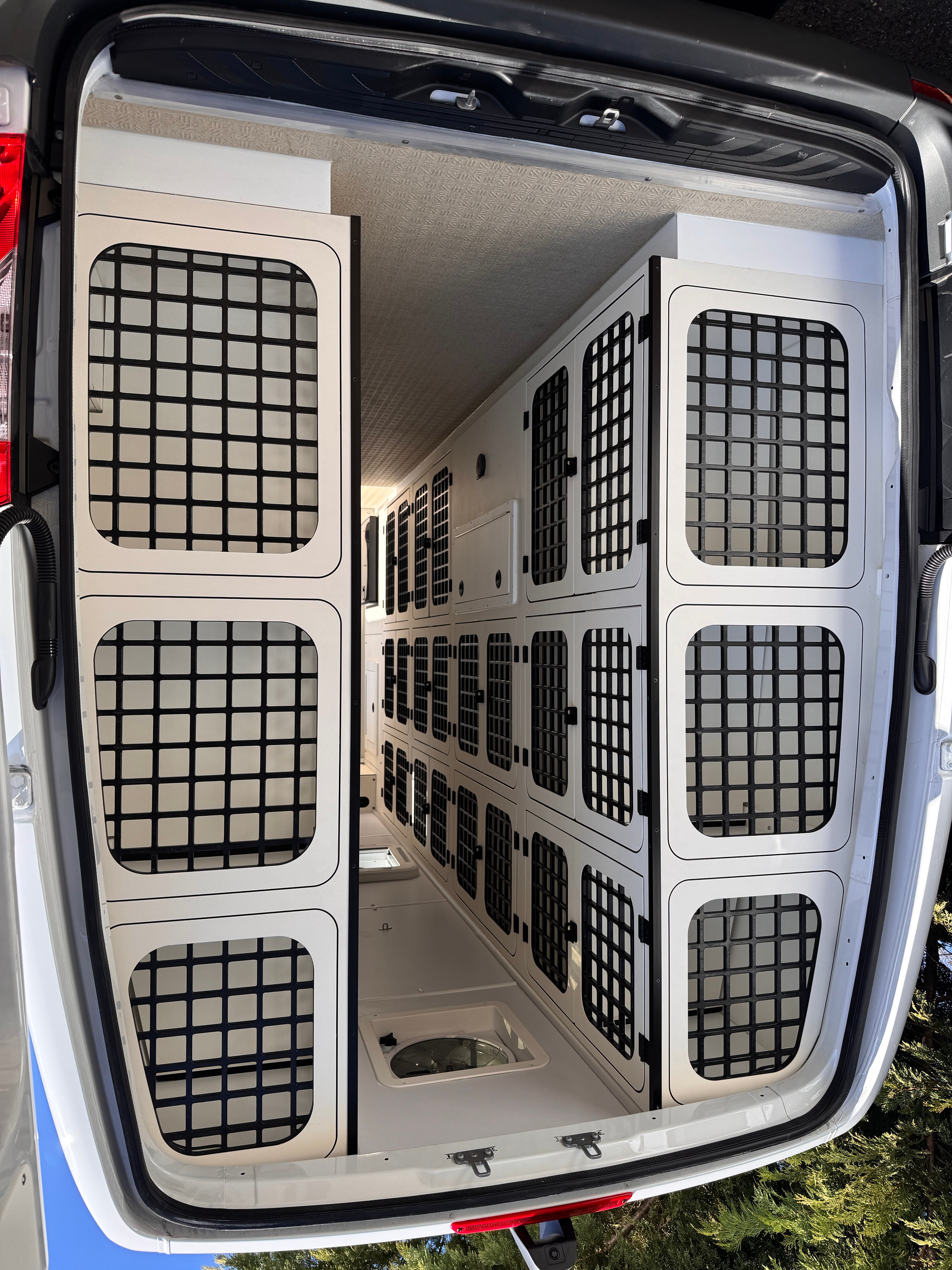 K9 transport Sprinter — rear doors open revealing the full multi-kennel array