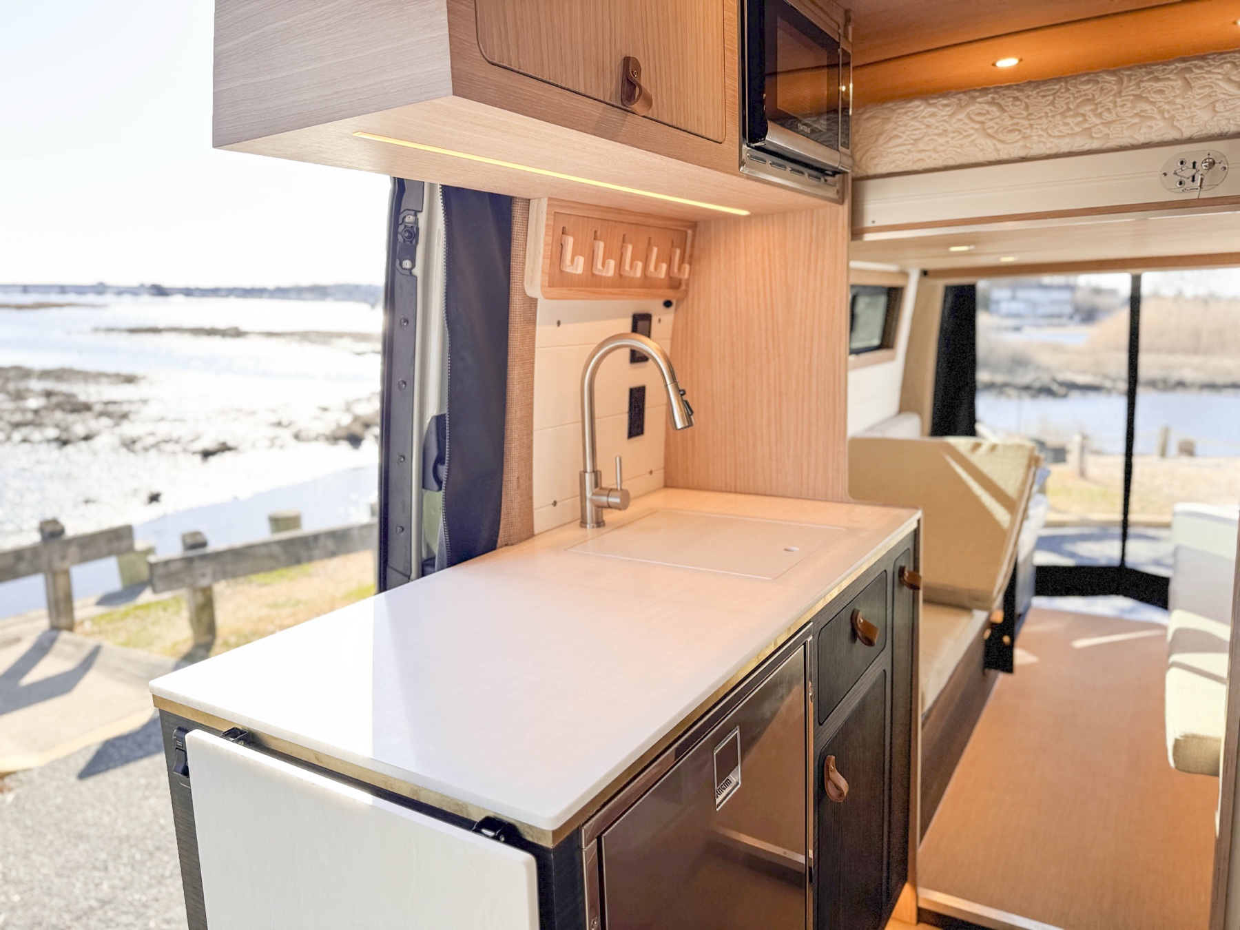 Loft campervan galley looking out at a marina — built for the marine-grade world the van actually lives in