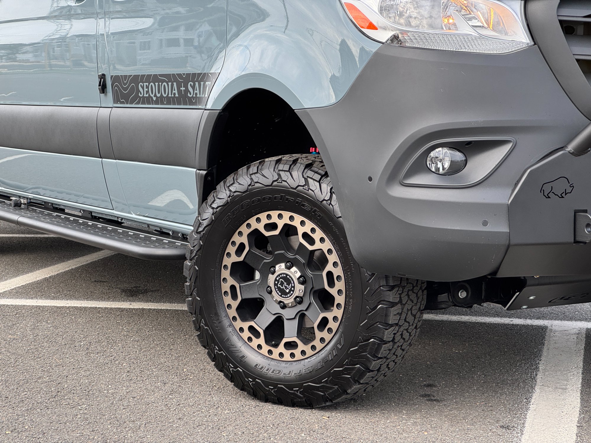 Loft Sprinter 4x4 front wheel detail — Black Rhino bronze wheels, BFGoodrich All-Terrain tire, and bull bar with Sequoia + Salt topographic rocker graphic