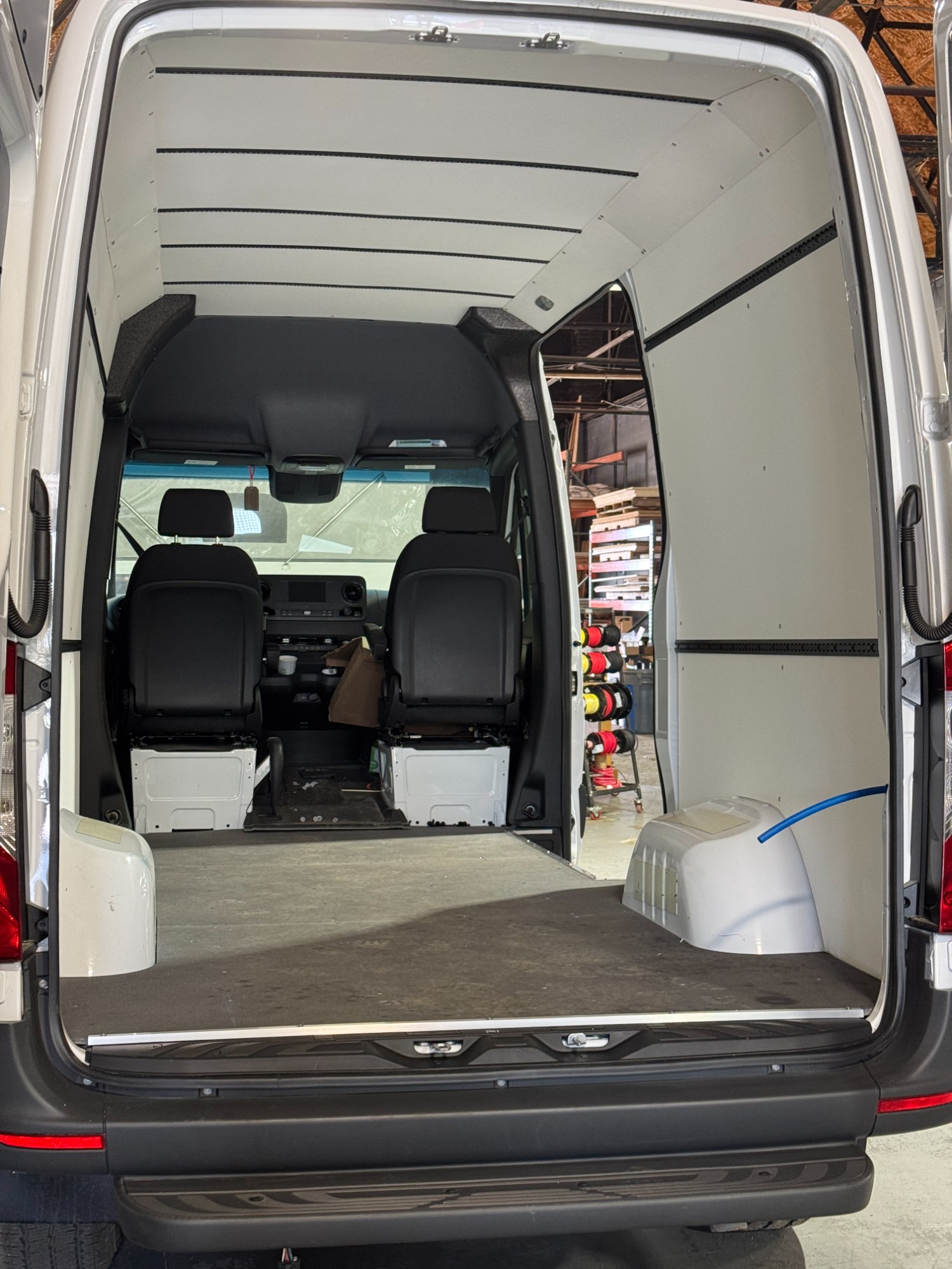 Empty Sprinter cargo van interior from the rear doors looking through to the driver cab — the starting point before Design and Discovery begins