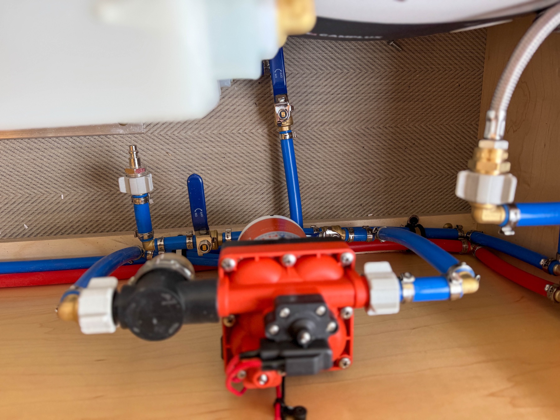 Marine-grade PEX plumbing manifold with brass shutoff valves and Shurflo water pump