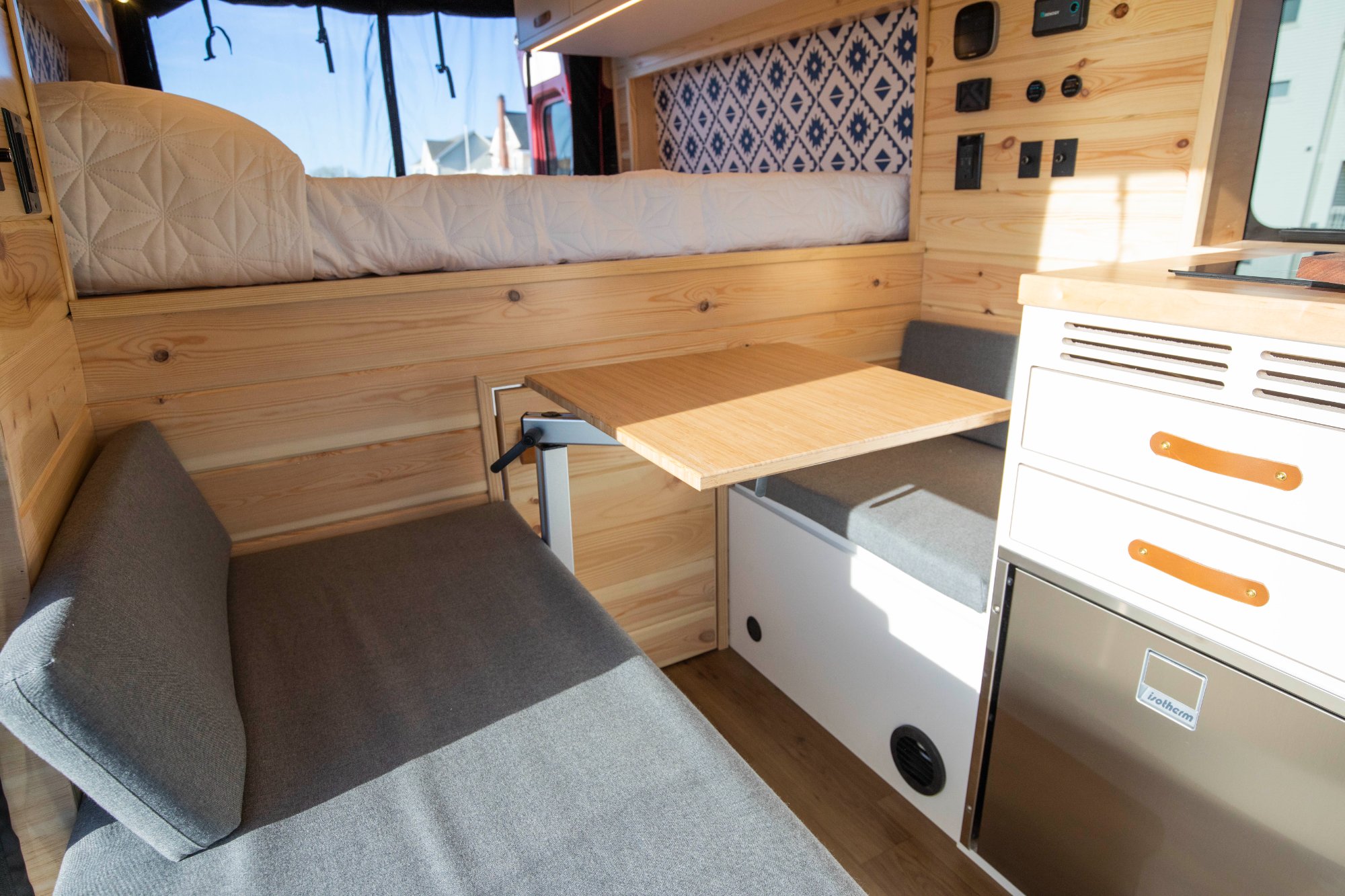 ProMaster interior with visible geometric blue-and-white pattern accent panel above bench seating — placeholder for Wild Flower geometric green-on-white pattern accent wall