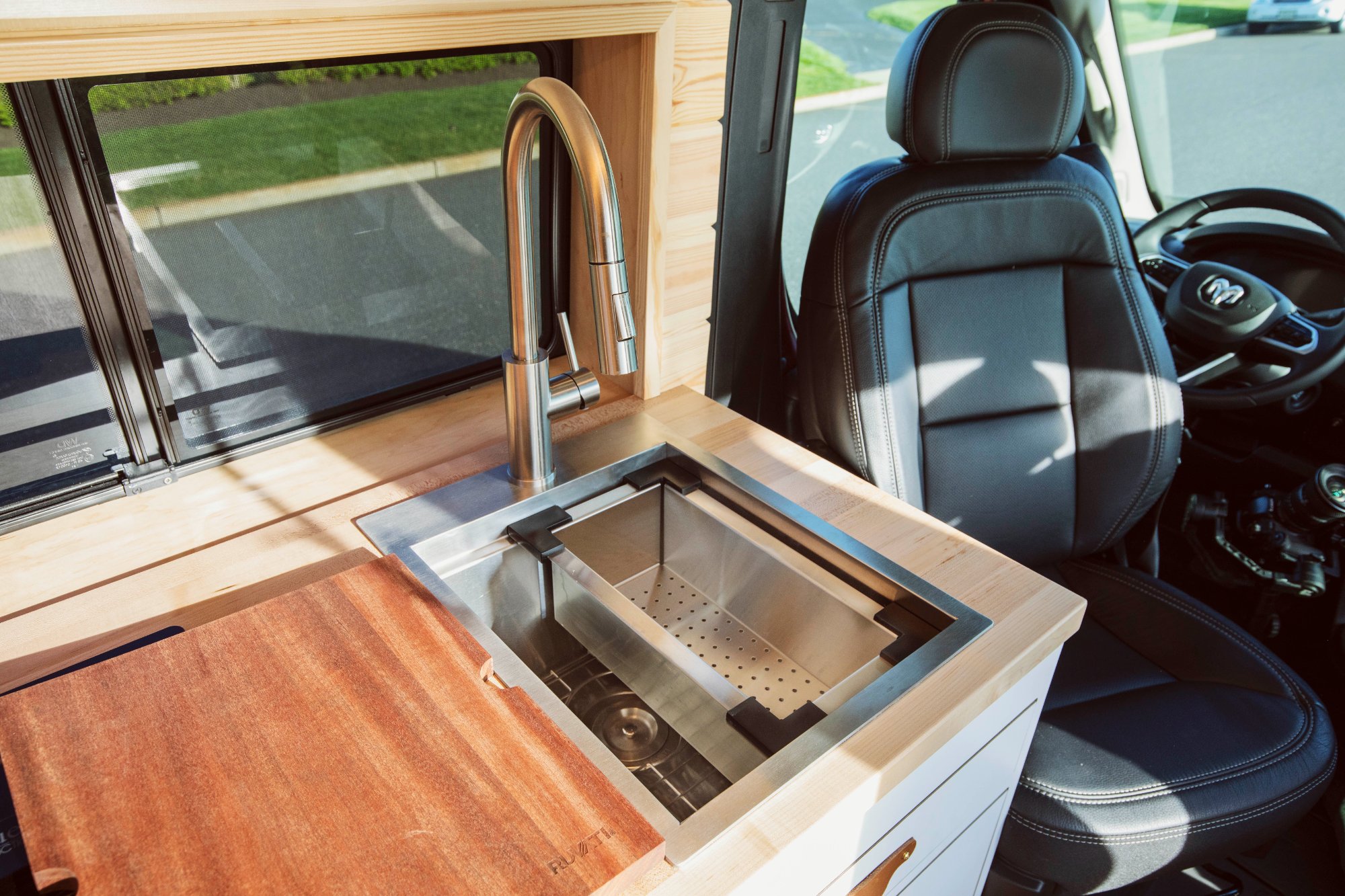 ProMaster galley with butcher-block counter, stainless sink, pull-out cutting board — placeholder for Wild Flower galley with sage cabinetry and pine countertop