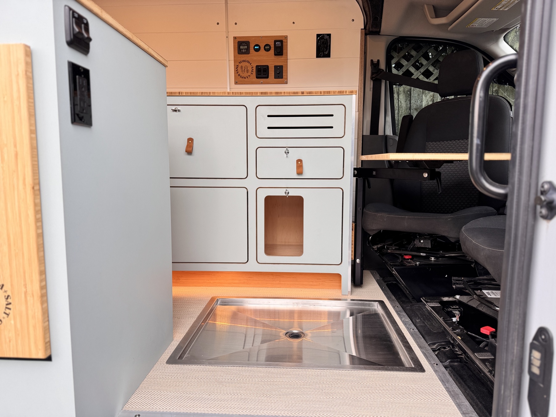 Scout campervan front interior view — power panel, galley sink, and finished floor showing the Weekend Power Foundation systems