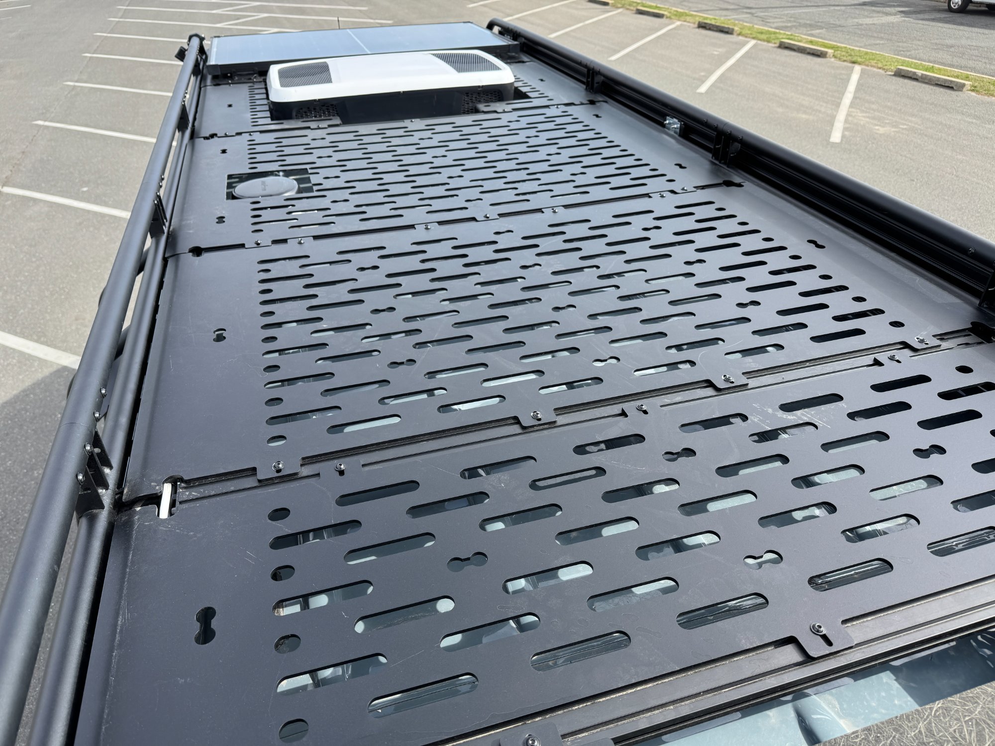 Sprinter campervan rooftop with perforated cargo rack and Dometic air conditioner mounted at front